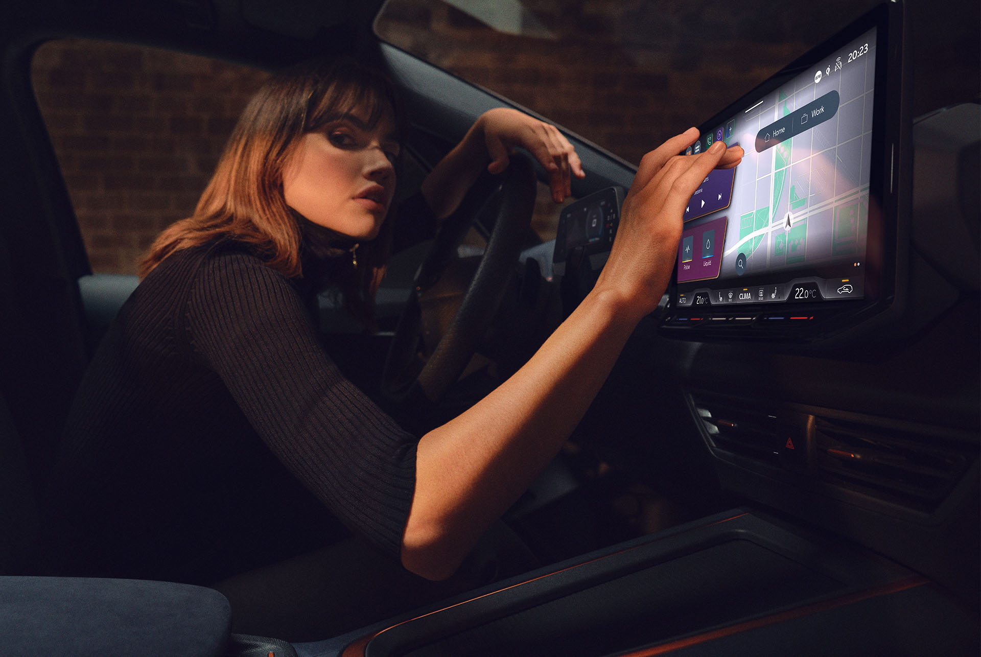 Dona dins un CUPRA Born utilitzant el tauler de control i la pantalla d'infotainment