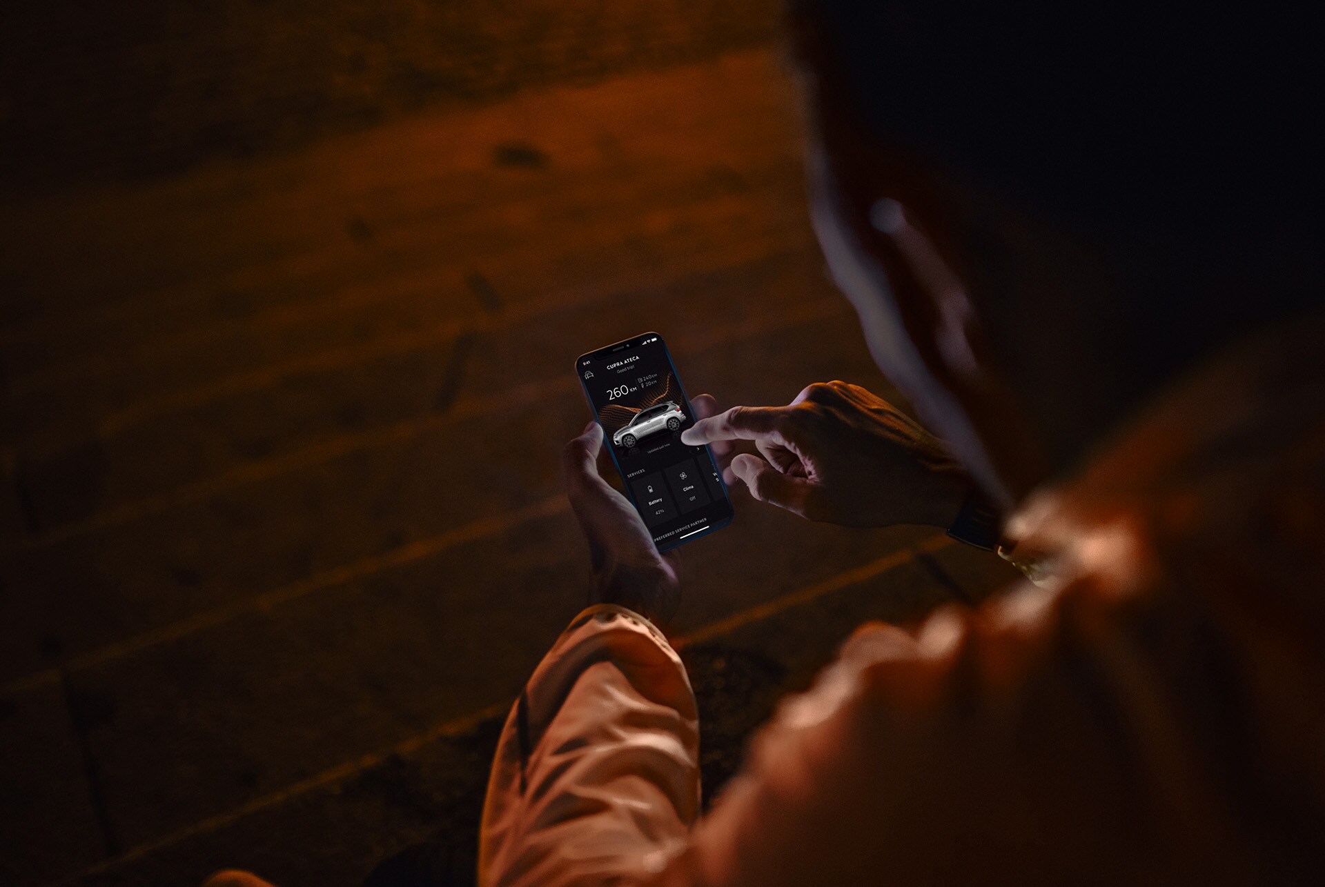 Els serveis en línia de CUPRA CONNECT incorporen una gamma de solucions per afrontar els reptes de la vida moderna. Una persona asseguda a les escales a la nit, utilitzant un smartphone il·luminat per la pantalla.