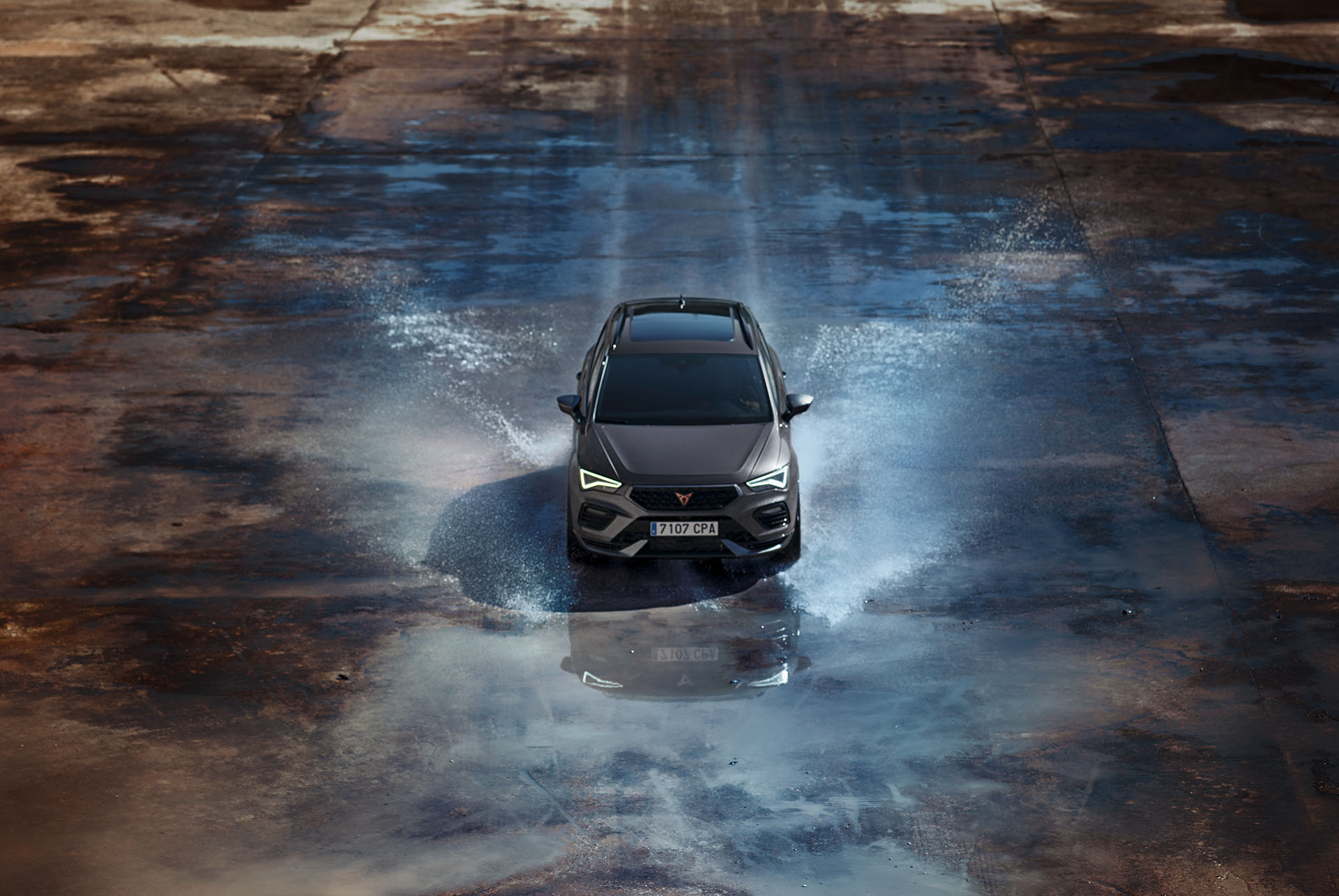 Vista frontal del CUPRA Ateca circulant per l'aigua, mostrant el seu capó accentuat, fars LED complets, detalls en alumini fosc i frens de rendiment amb pinces Brembo.