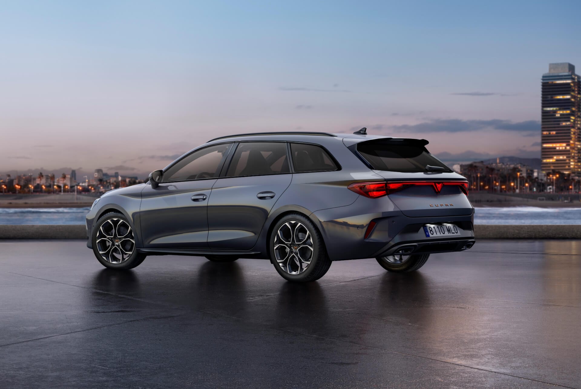 Vista posterior del nou model Cupra Leon Sportstourer 2025 en color gris brillant amb control dinàmic del xassís i llandes d'aliatge en negre i coure. Ciutat al fons al capvespre.