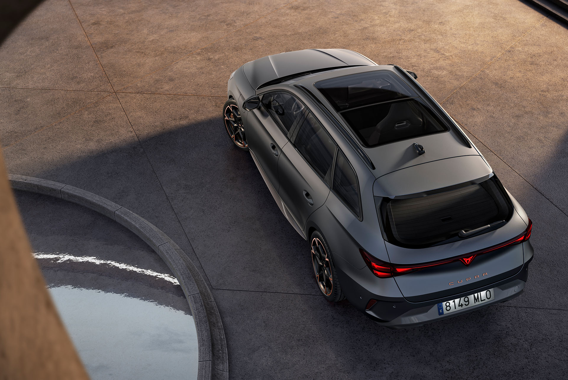  Tecnologia del nou Cupra Leon Sportstourer 2025, estacionat sobre ciment, ull d'àguila amb sostre escorredor panoràmic i porta gran posterior elèctrica.