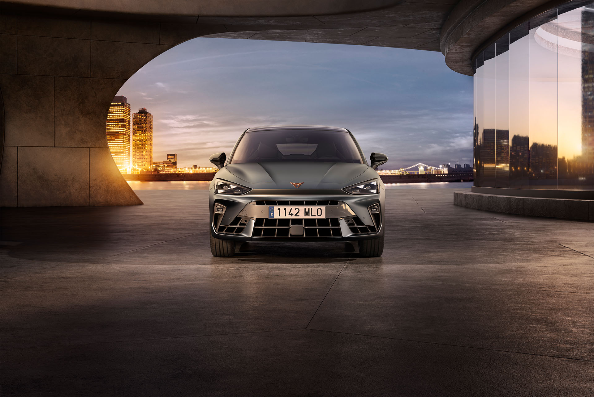 Novas versions i equipament dels models Cupra Leon 2025, entrades d'aire, fars d'ull triangle, posta de sol, panells de vidre, arquitectura i cels blaus.
