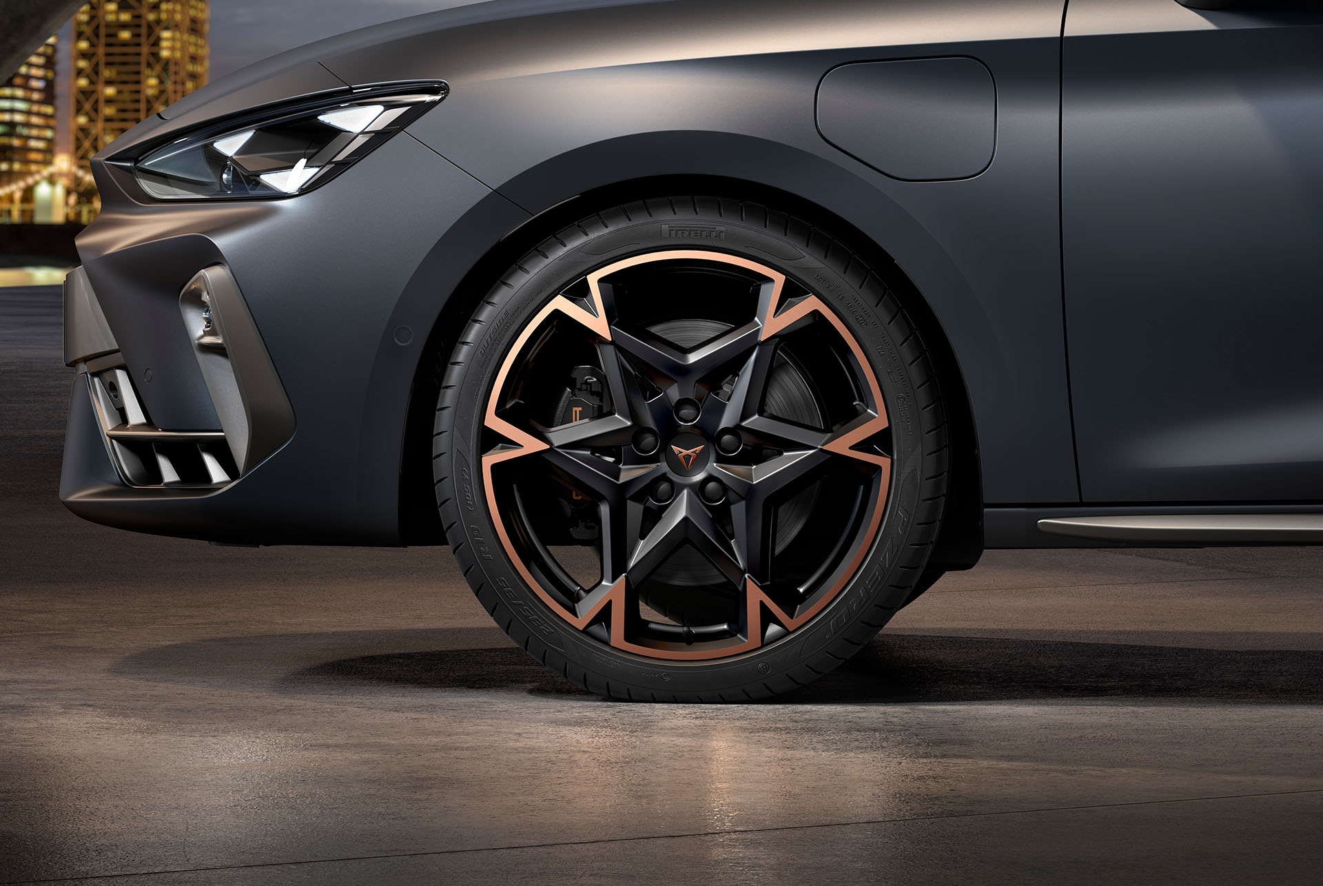 Vista lateral davantera esquerra de la llanda d'aliatge mecanitzada en negre i coure per al nou Cupra Leon 2025, pneumàtics, fars característics i carrosseria grisa mat