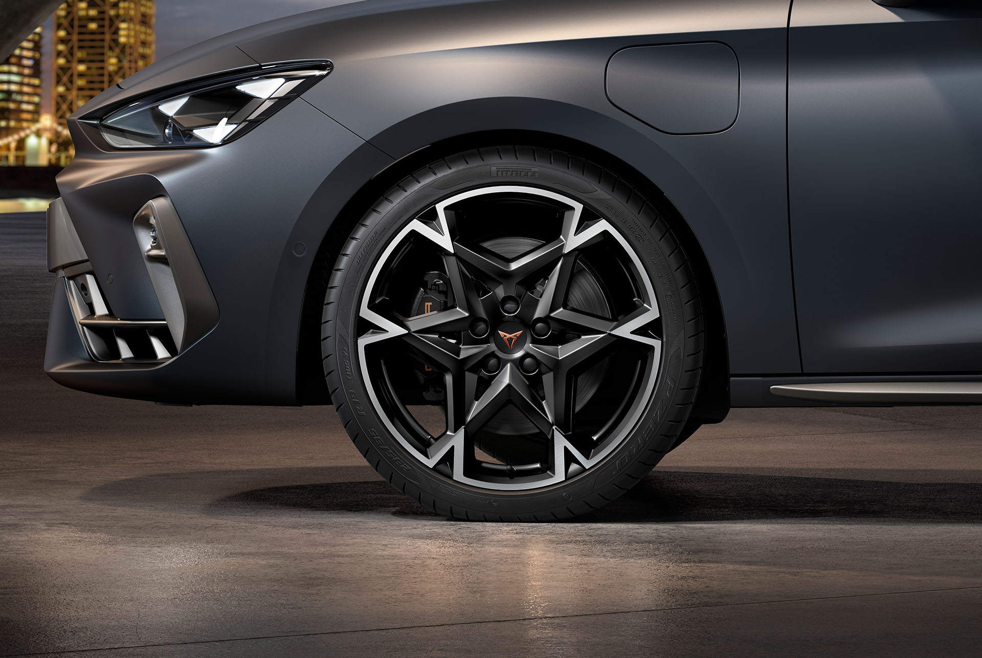 Vista lateral davantera esquerra de la llanda d'aliatge mecanitzada, polar en negre i platejat per al nou Cupra Leon 2025, pneumàtics, fars característics i carrosseria grisa.