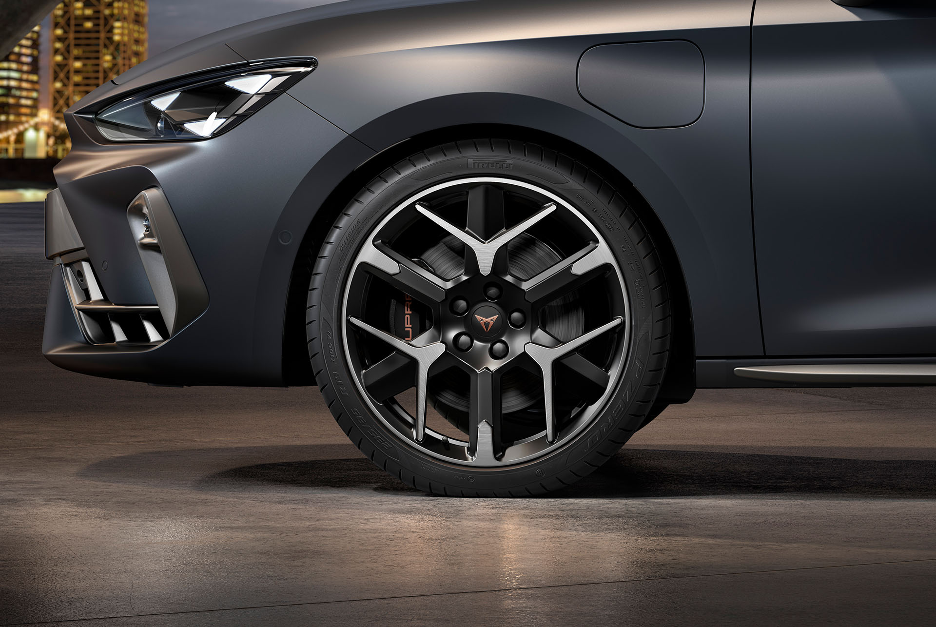 Vista lateral davantera esquerra de la llanda d'aliatge, forjat en platejat i negre per al nou Cupra Leon 2025, pneumàtics, fars característics i carrosseria grisa mat. 