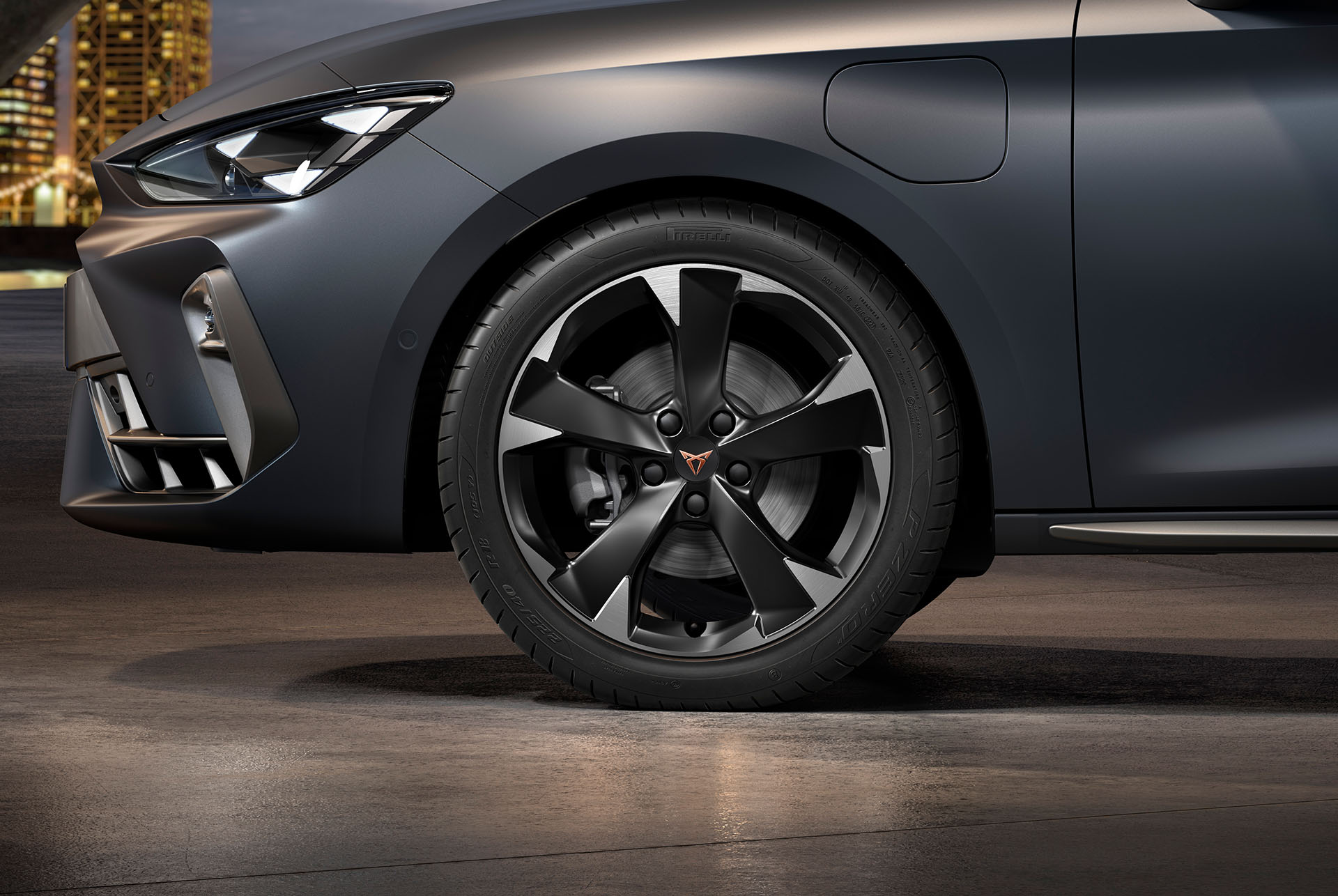 Vista frontal lateral de les llandes esquerres d'aliatge mecanitzades Silver Garbi per al nou Cupra Leon Sportstourer 2025, pneumàtics, fars característics i carrosseria grisa mat