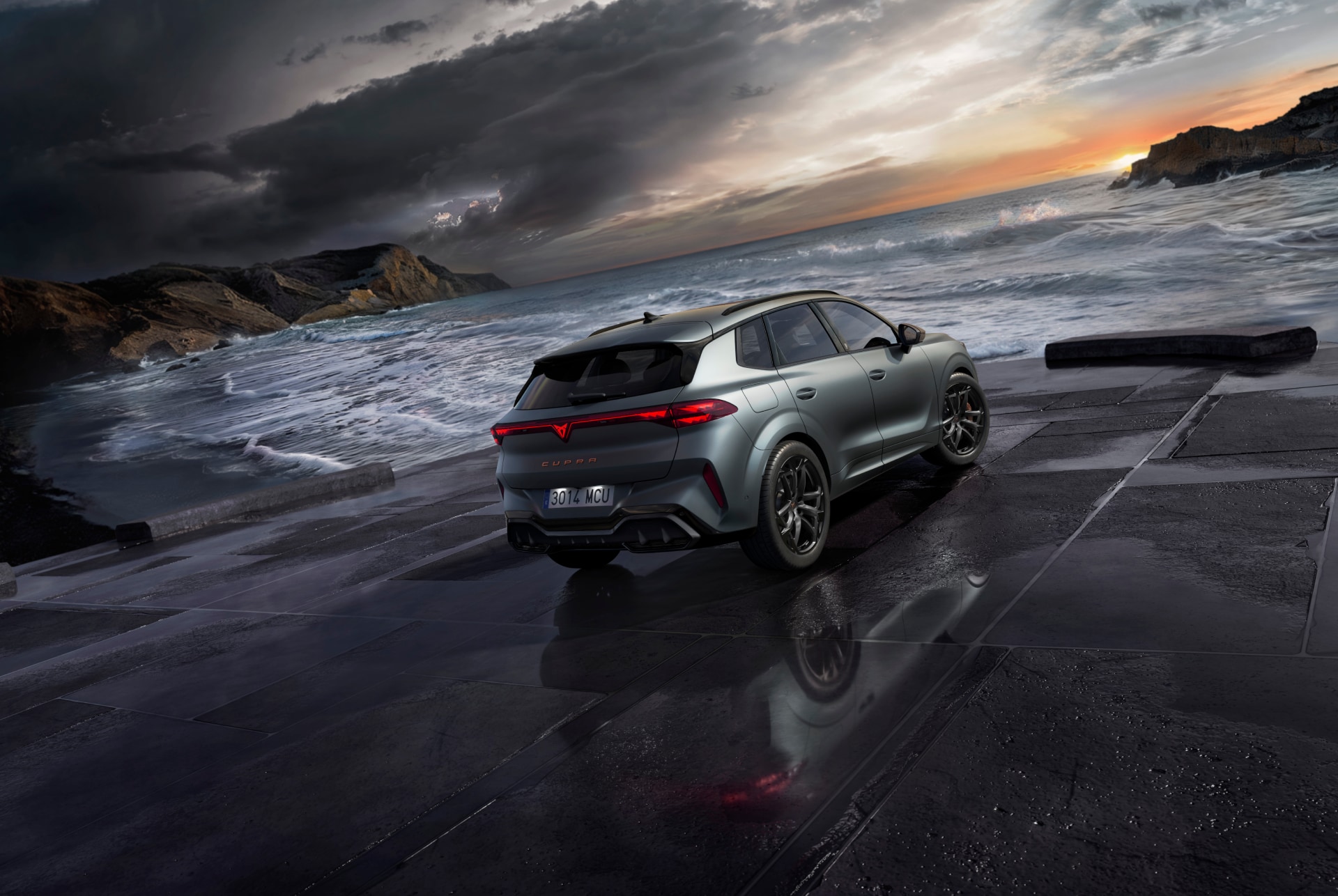 SUV híbrid Cupra Terramar, nou model 2025, angle de visió posterior, amb elegants llums posteriors amb el logotip de Cupra, modernes llandes d'aliatge i una carrosseria esportiva, sobre un paviment mullat al costat de la mar.