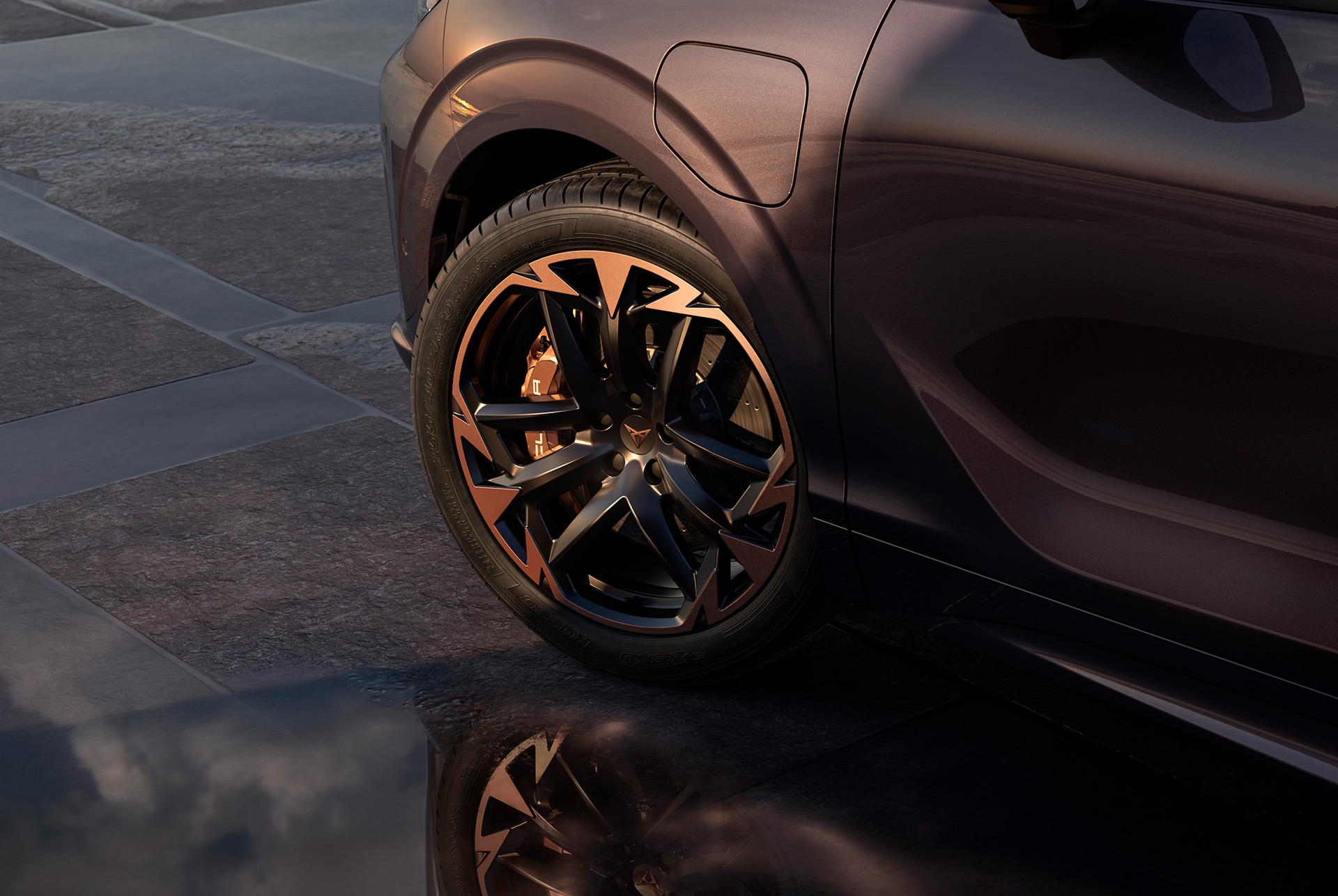 Llandes d'aliatge Vortex Copper de 50,8 cm (20") en negre amb detalls en coure en el nou CUPRA Terramar. En el fons hi ha una vorera de rajoles i part de la carrosseria brillant i fosca del cotxe.